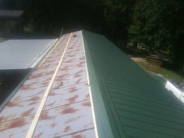 Old rusted panels beside newly installed green metal roofing — Wind Damage Roof Repair by Roofing Brothers in Holland